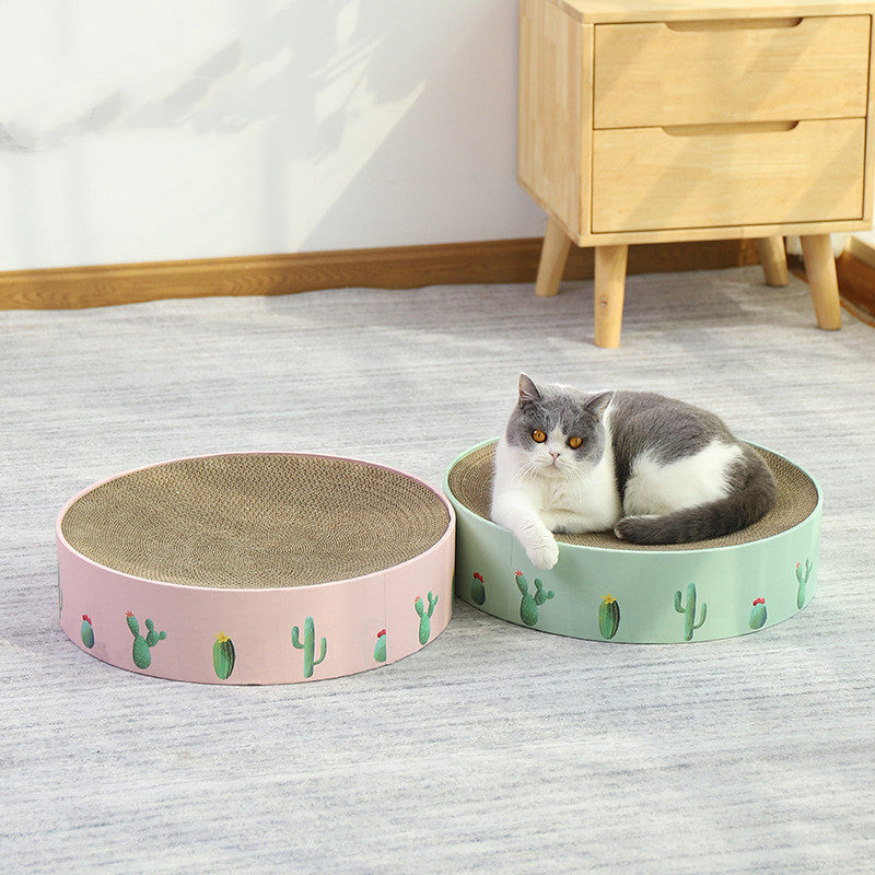 Cat lying on a round, patterned cat bed with another similar bed beside it in a room.